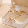 Gold floral open cuff armlet jewelry with delicate white petals displayed in a light box.