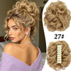 A woman shows off a voluminous curly messy bun hairstyle with a hair clip accessory.