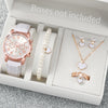 A box contains a pink quartz wristwatch with a leather strap, a pearl necklace, and a gold heart pendant.