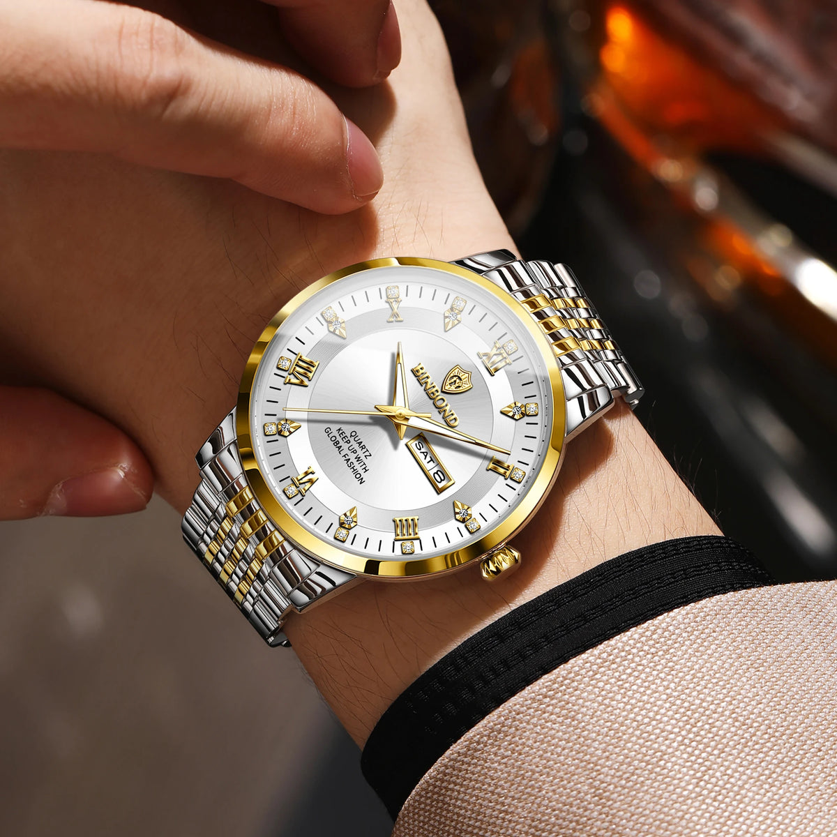 A close-up shot of a gold-toned luxury quartz wristwatch with a silver bezel and textured metal bracelet on a person's wrist.