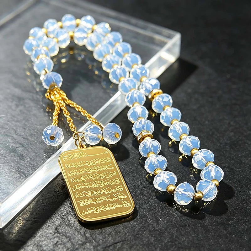 A necklace featuring light blue glass beads and a gold-colored pendant engraved with Arabic text.