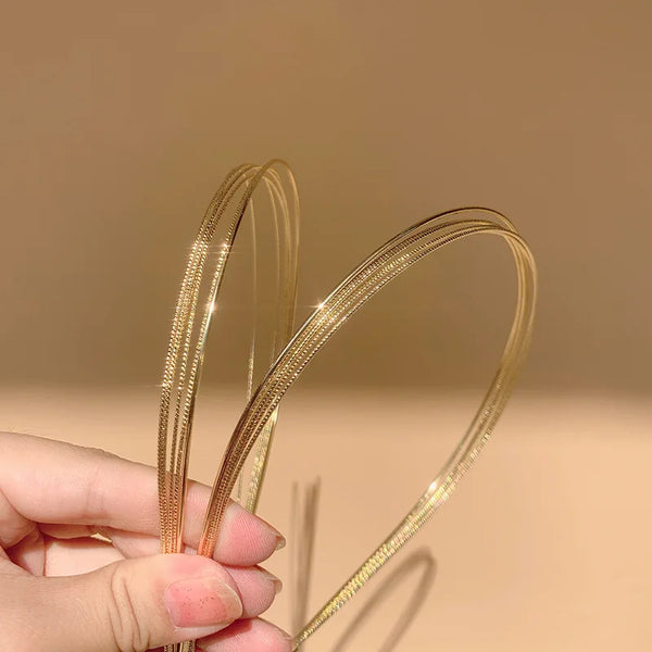 A hand holds a piece of multi-layer gold alloy hair hoops, showing the delicate wire structure.