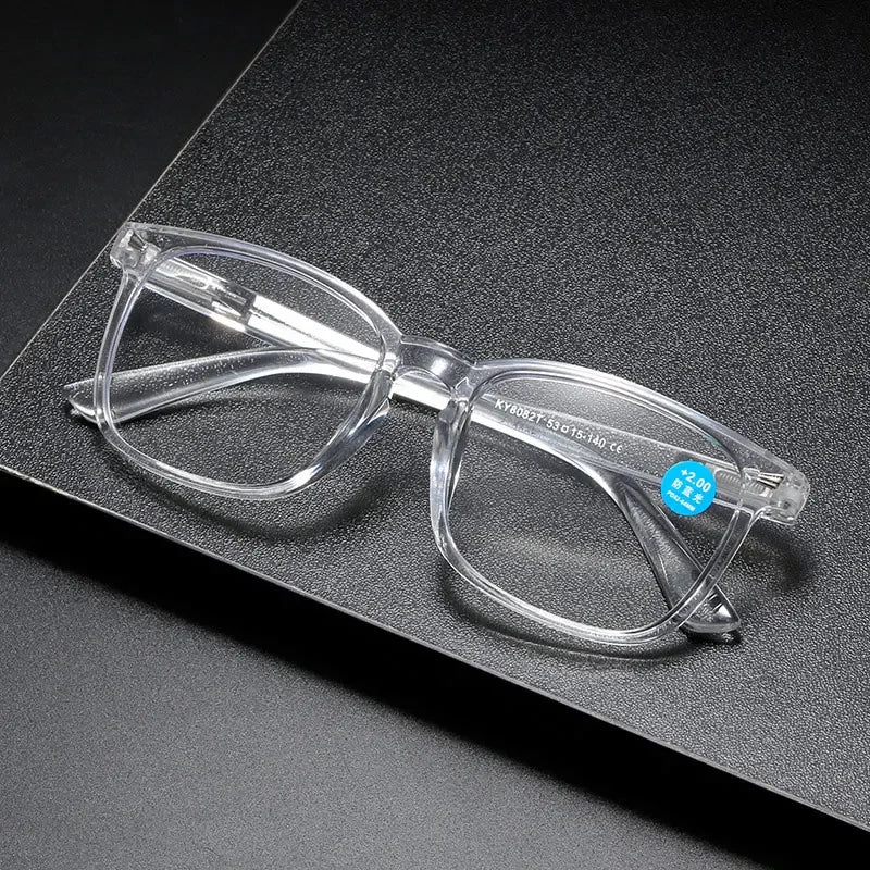 Gafas de lectura de plástico transparente con marco plateado sobre una superficie oscura.