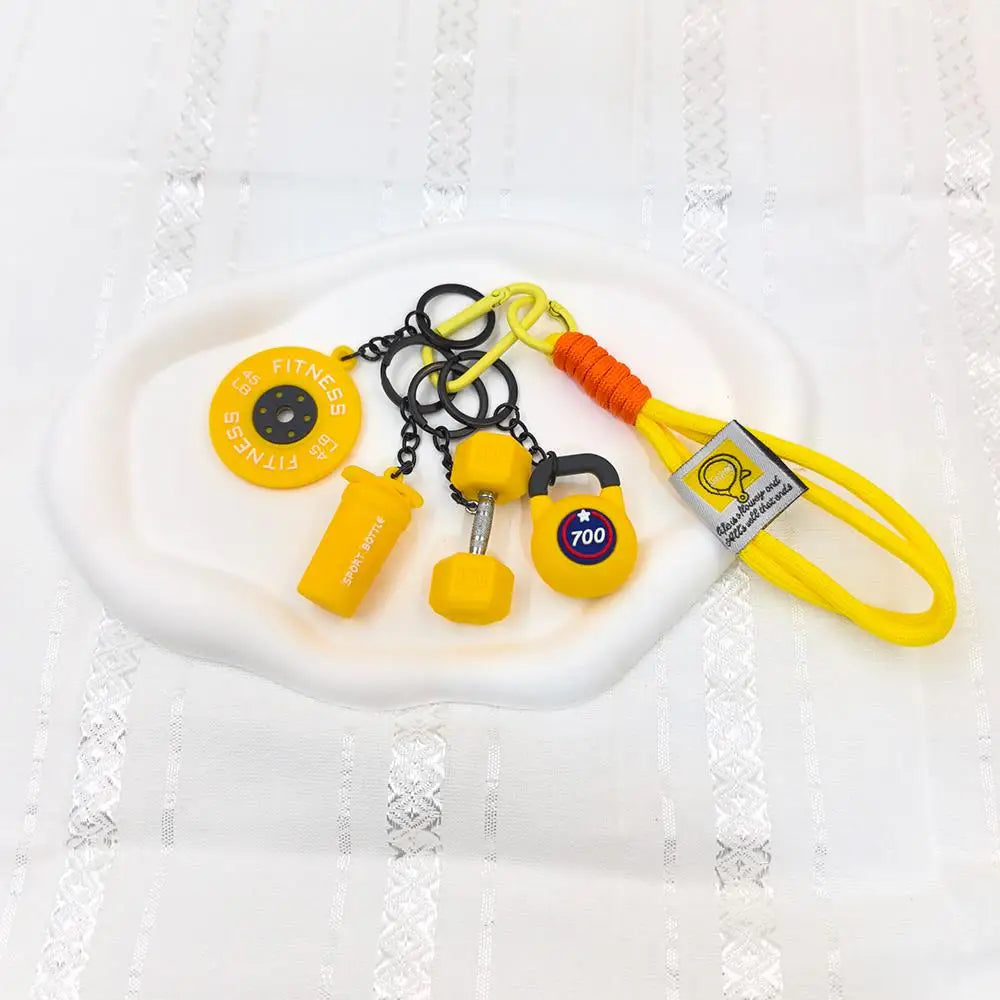 A collection of five yellow fitness keychains and weightlifting accessories on a white plate.
