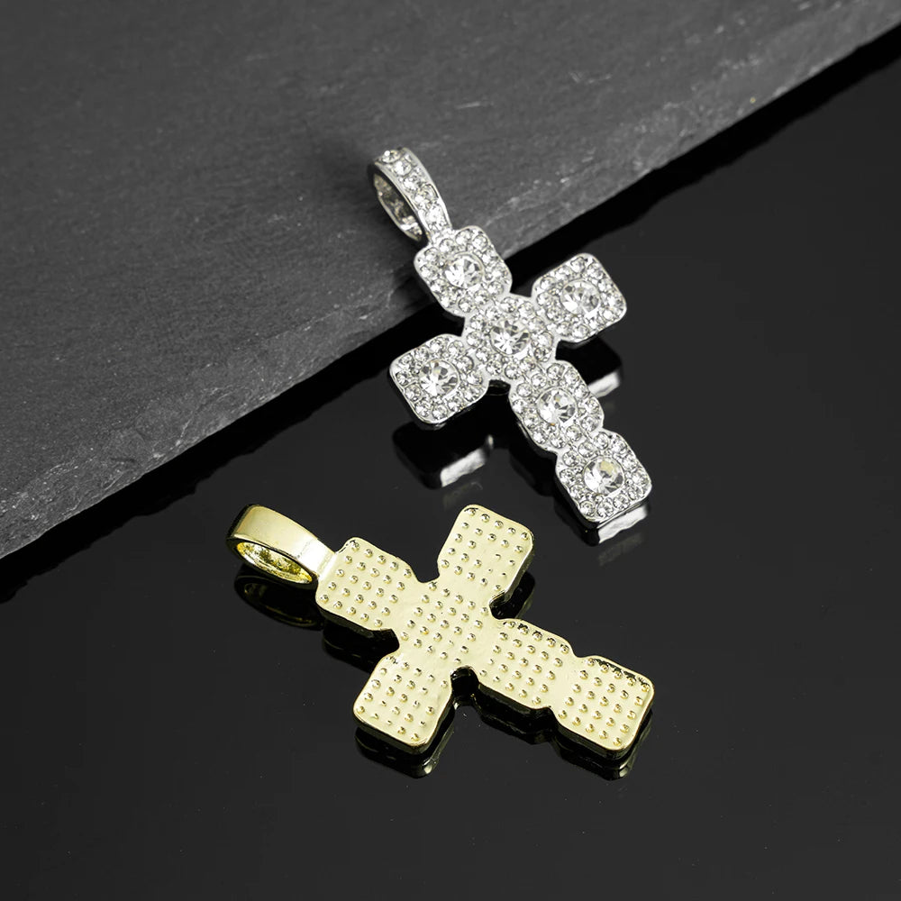 A pair of cross pendant necklaces, one silver and one gold, set against a dark background.