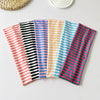 Collection de bandeaux pour cheveux colorés et rayés, disposés horizontalement sur une surface blanche.