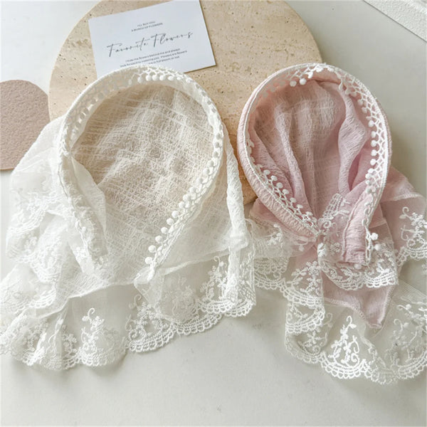 A pair of pink and white lace knit headscarves or hairbands displayed on a light surface.