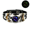 Schwarzes Lederarmband mit silbernen Perlen, goldenen Akzenten und einem zentralen dunklen Stein mit leuchtend violetten Lini