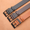 A close-up of a brown leather belt with a black buckle lying on a tan surface.