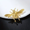 Broche dorée en forme d'abeille avec ailes et corps détaillés.