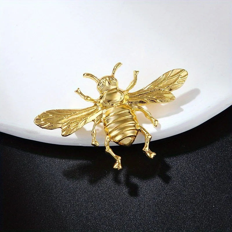 Broche dorée en forme d'abeille avec ailes et corps détaillés.