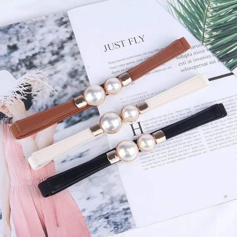 Ein Set eleganter Vintage-Perlengürtel in braun, Creme und schwarz Leder auf weißem Papier.