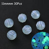 A collection of 30 iridescent glow-in-the-dark acrylic beads scattered on a dark surface.