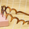 A set of wooden zigzag headbands or hair combs for face concealment displayed on a light pink surface.
