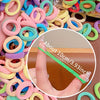 A close-up of colorful elastic hair bands, including pink, blue, yellow, and green, with a measurement guide showing about 10