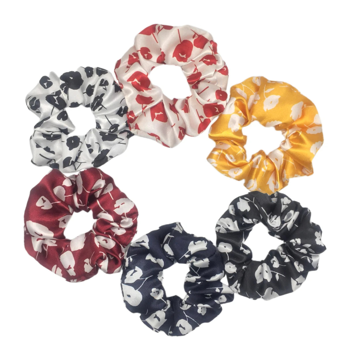 Un set de seis gomas para el pelo con estampado floral de satén en varios colores, incluyendo negro, blanco, rojo y amarillo