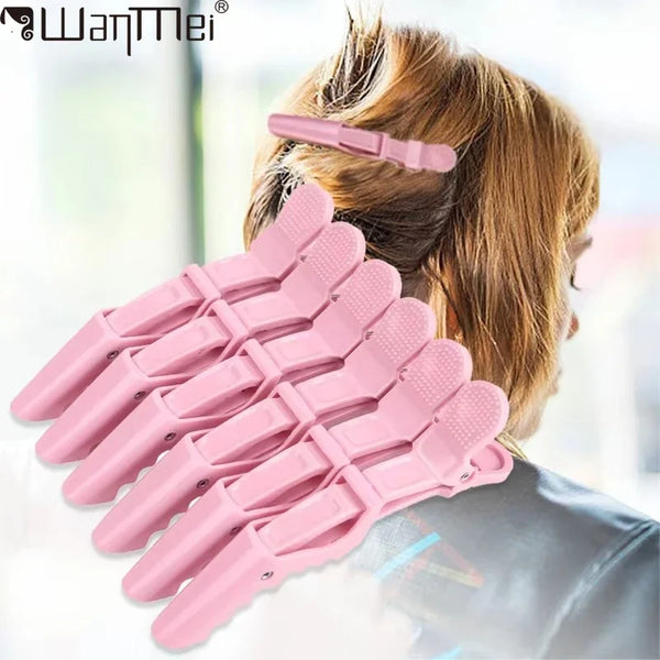 A set of six pink alligator hair sectioning clips being used to style hair.