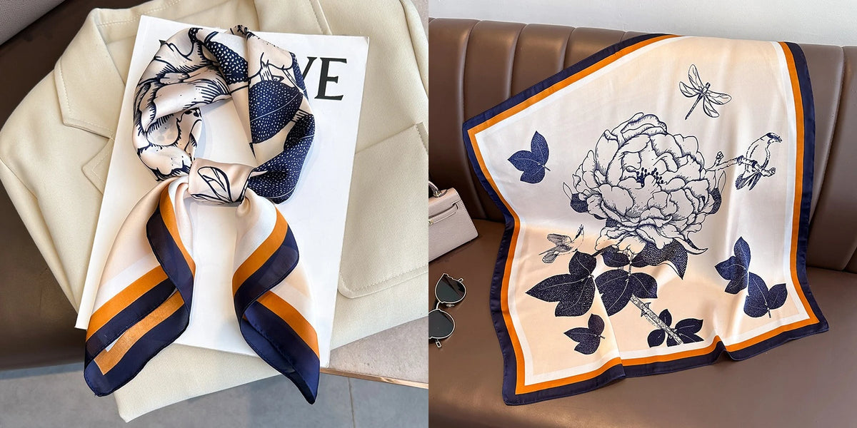 A beige silk scarf with a floral print featuring blue butterflies and leaves, tied in a bow.
