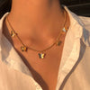 Collier minimaliste orné de petits charms papillons, porté sur un t-shirt blanc.