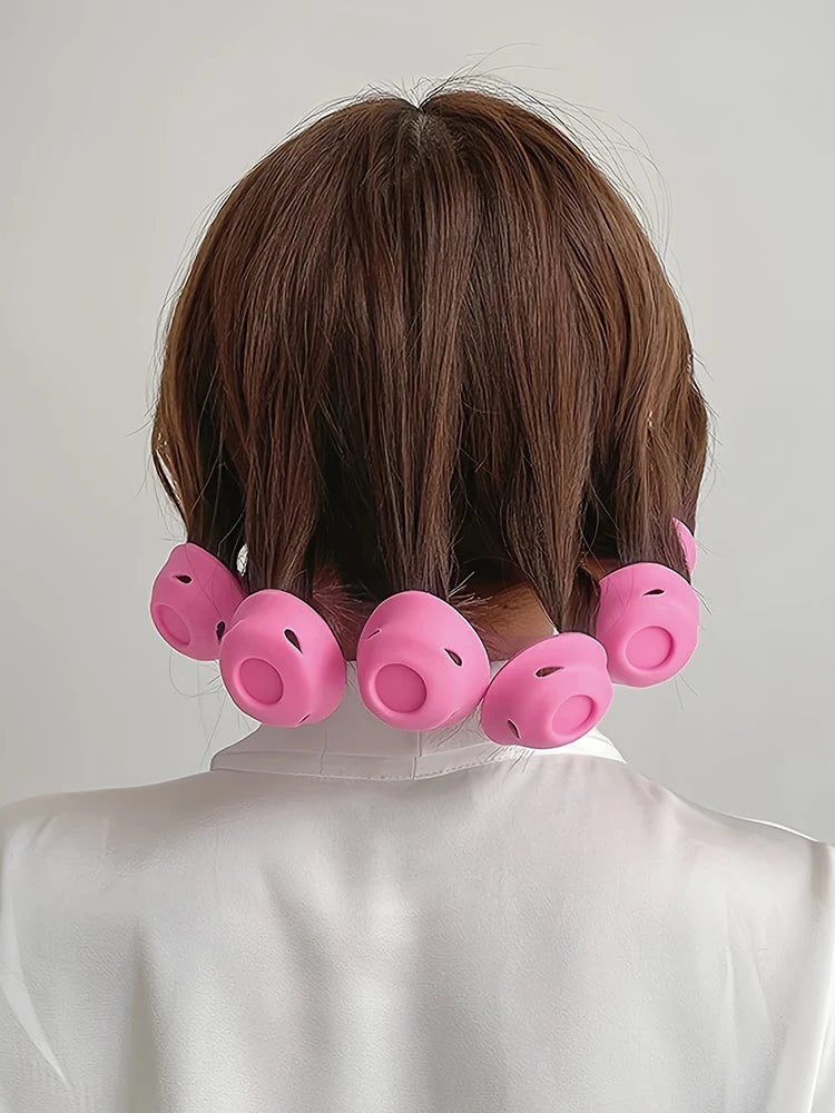 A set of pink heatless magic hair curlers placed on the back of a person's neck.