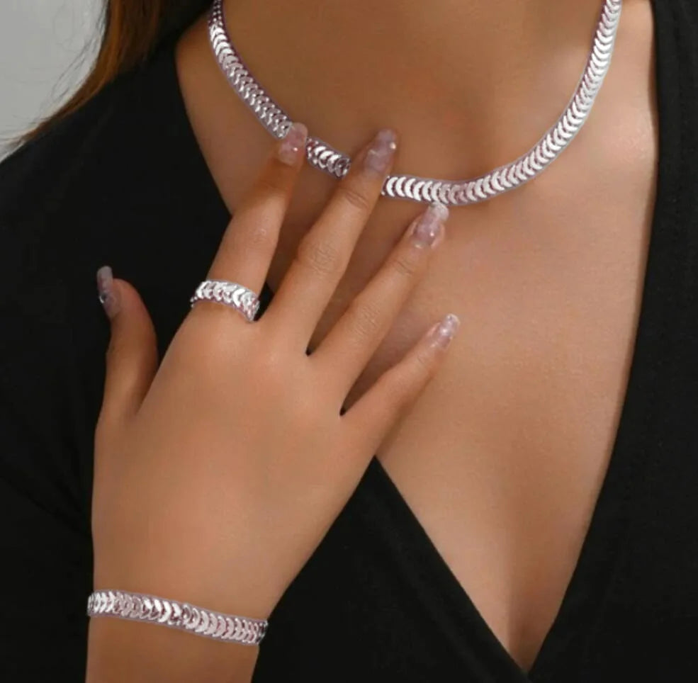 A close-up of a woman wearing a silver rhinestone heart charm necklace and bracelet against a black top.