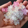 A handful of luminous glow-in-the-dark acrylic beads in shades of pink, purple, and pale green are held in a hand.