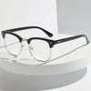 Un par de gafas con montura negra y lentes transparentes sobre una superficie blanca.