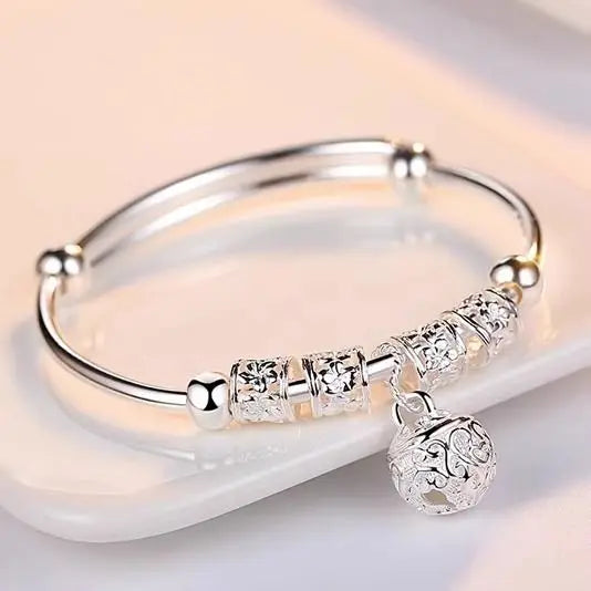 A stack of nine two-tiered sterling silver bell bangles for women displayed on a white surface.