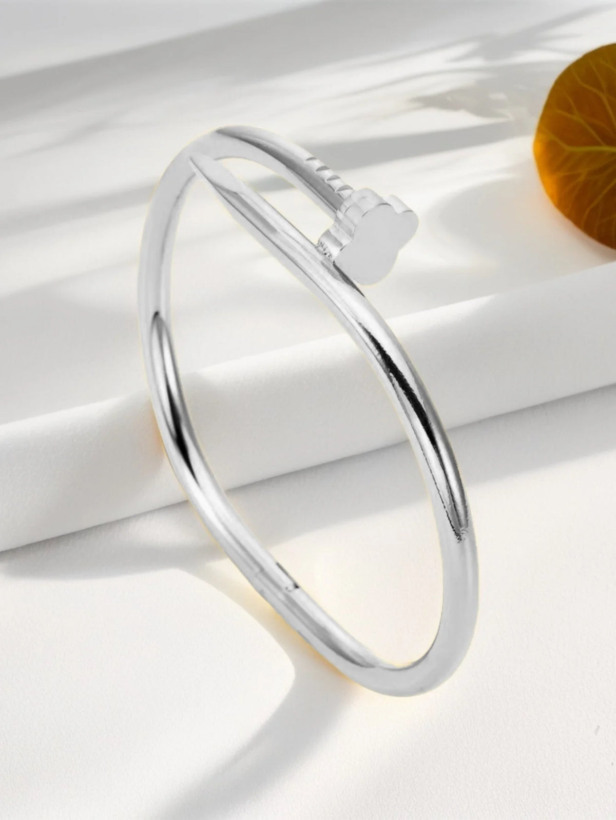 Silver stainless steel ring with a four-leaf clover charm resting on a white surface.