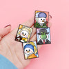 A hand holds a set of three cute animal enamel brooches featuring stylized cartoon characters.