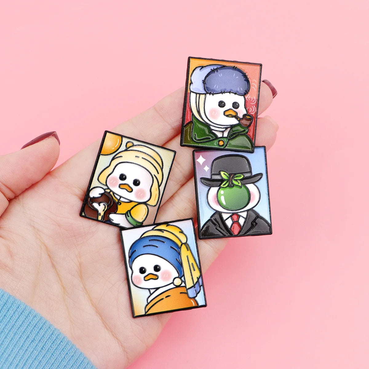A hand holds a set of three cute animal enamel brooches featuring stylized cartoon characters.