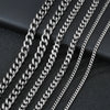 A close-up view of several silver-toned Cuban link chains arranged diagonally on a dark surface.