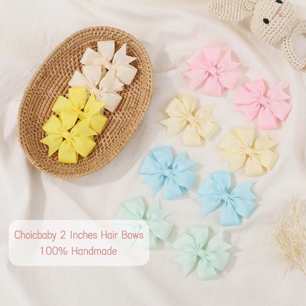 Assorted grosgrain ribbon hair bows in pink, yellow, and light blue are displayed on a beige background.