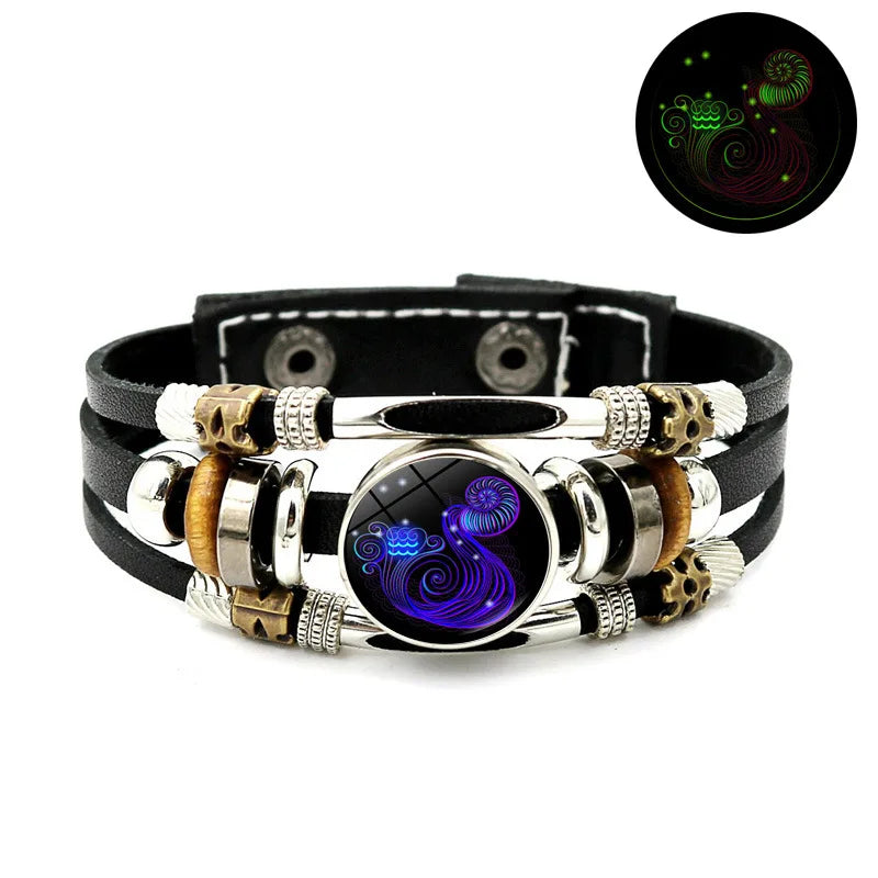 Schwarzes Lederarmband mit silbernen Perlen, goldenen Akzenten und einem zentralen blauen, irisierenden Stein.