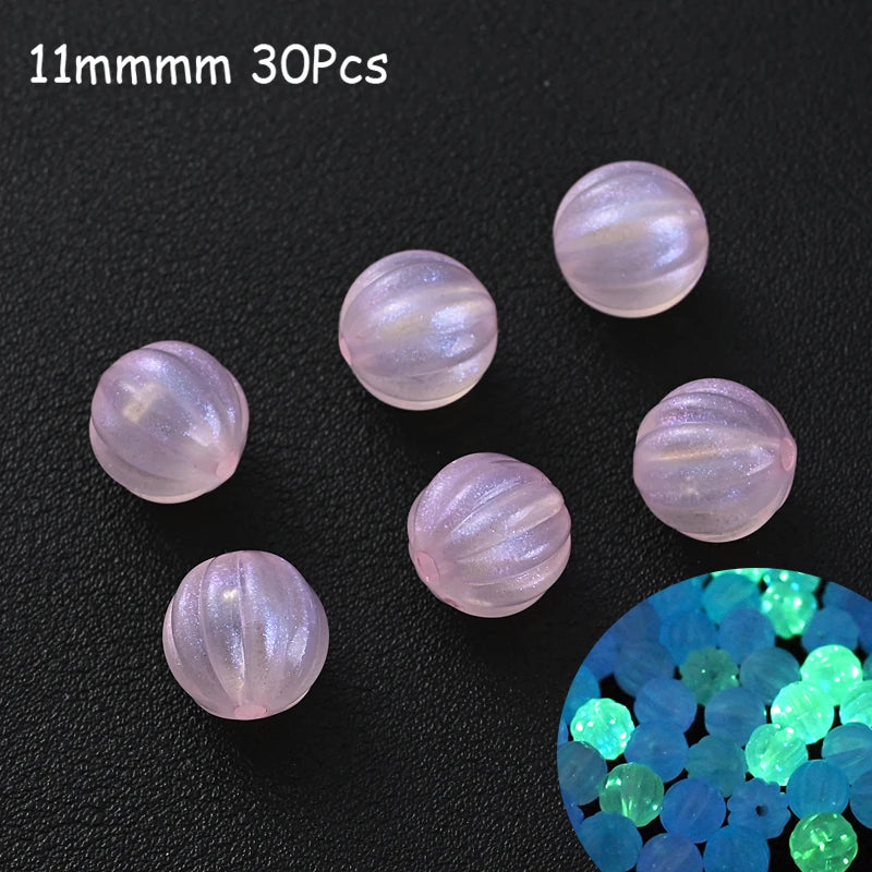 A collection of 30 iridescent pink acrylic beads scattered on a dark surface with a cluster of glowing blue beads.