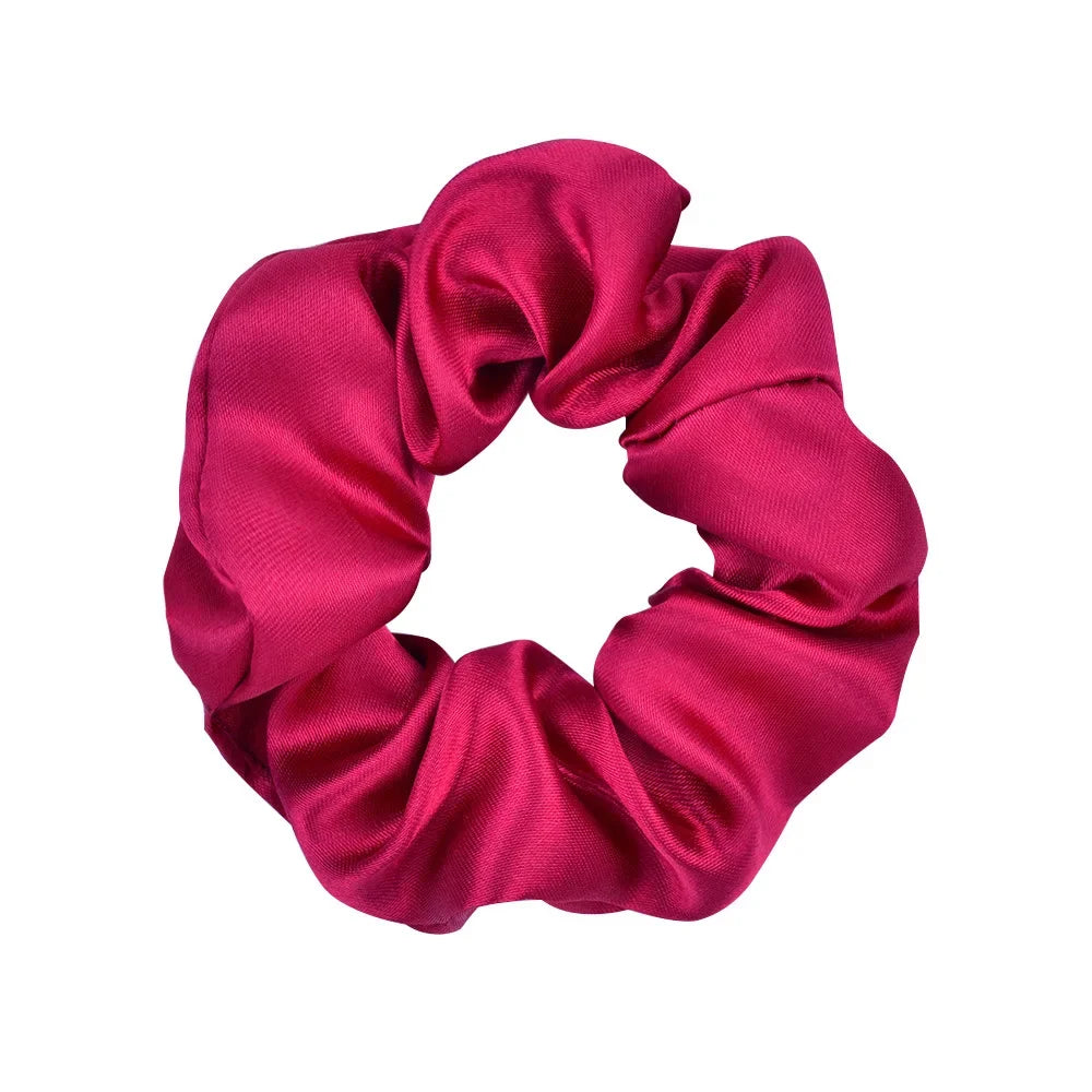 A vibrant magenta satin scrunchie tied in a voluminous, ruched style.