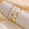 Three gold-plated stainless steel bracelets worn on a wrist.