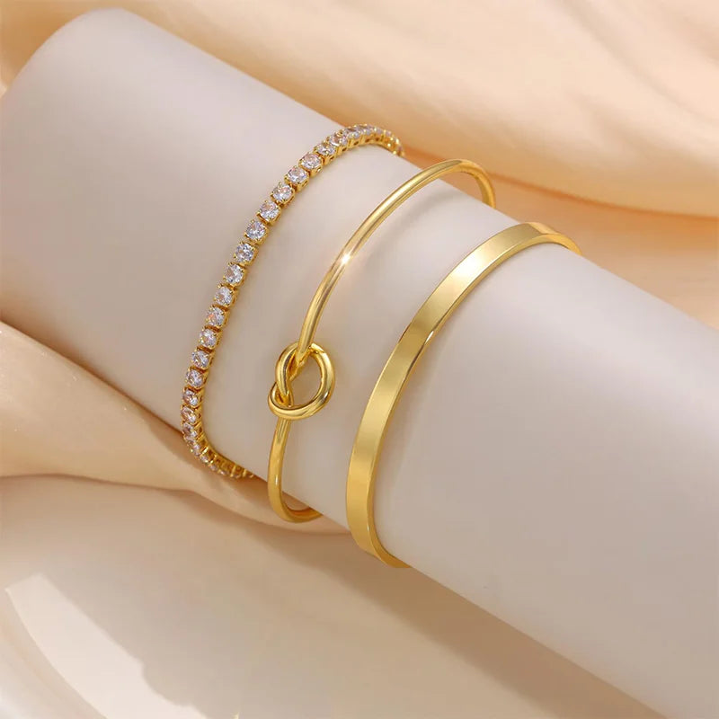 Three gold-plated stainless steel bracelets worn on a wrist.