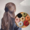 A collection of elegant horsetail hair clips in various shades of brown, beige, and orange arranged on a wooden plate.
