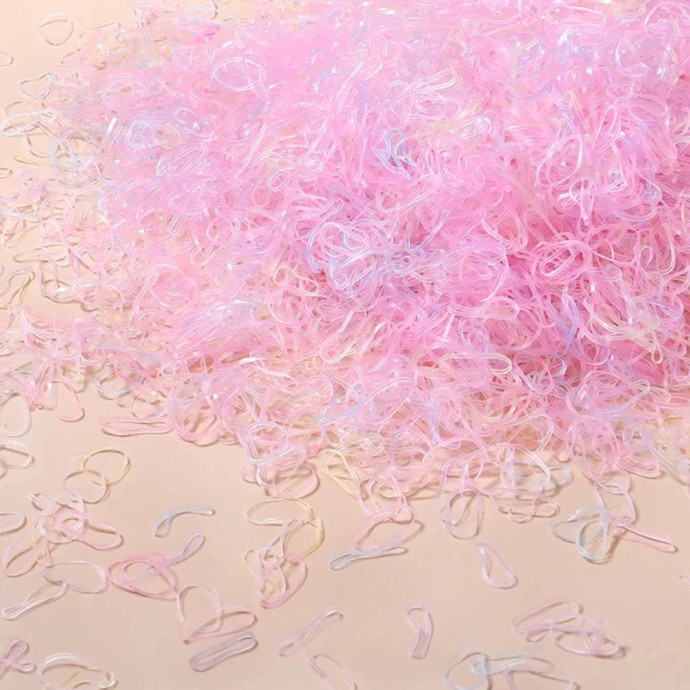 A pile of colorful pink and clear disposable rubber hair ties for kids