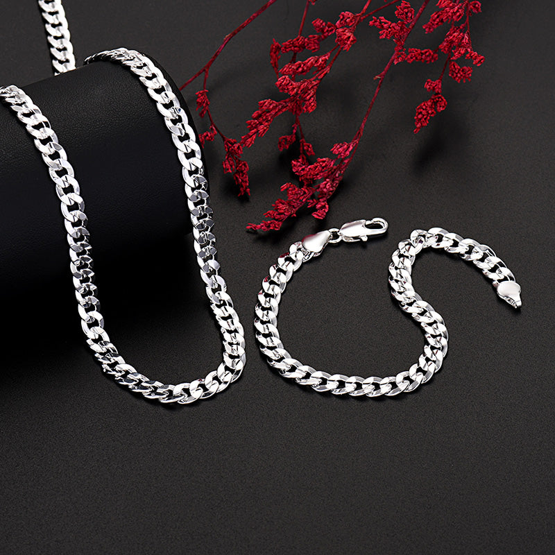 Un ensemble de colliers et bracelets en argent sterling, présentés sur un fond sombre avec du feuillage rouge.