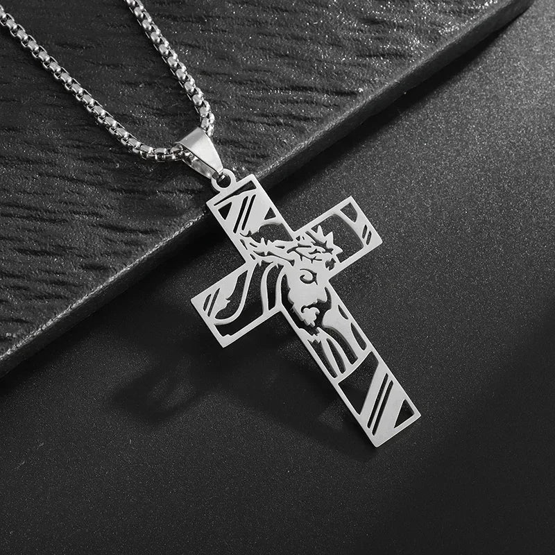 Silver cross amulet necklace with a detailed depiction of Christ's face and crown on a dark background.