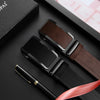 A black leather belt with a brown strap and a silver automatic buckle is displayed on a dark surface.