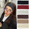 A woman models various black and white polka dot stretch hairbands on her head.
