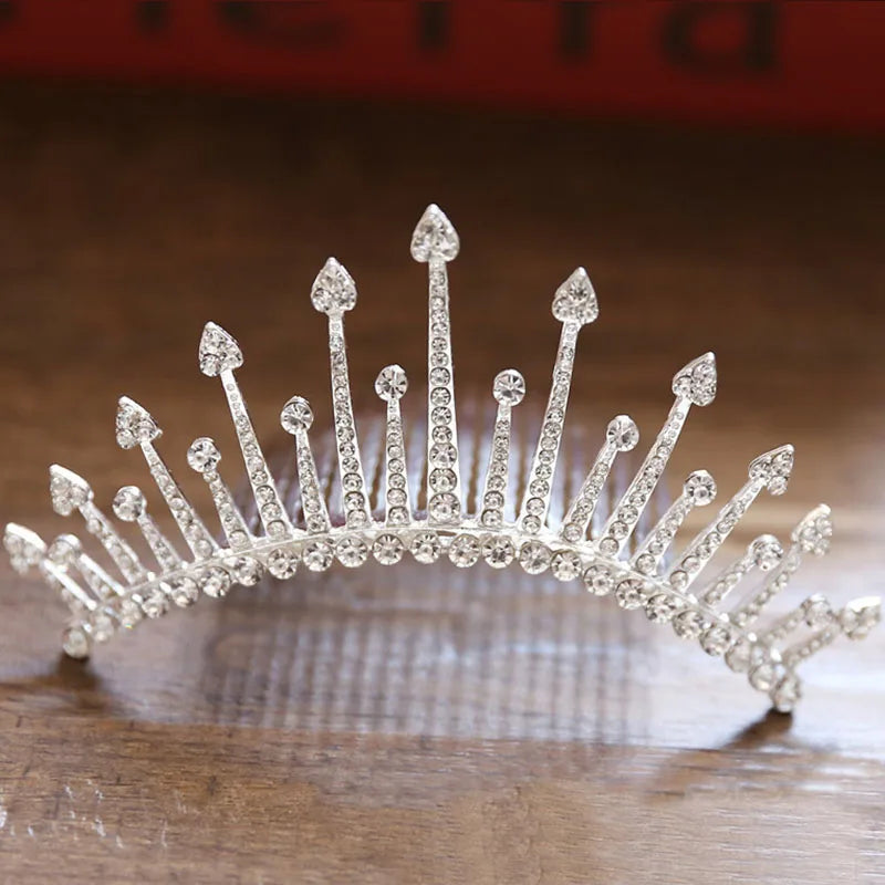 A sparkling crystal princess tiara hair comb for women displayed on a wooden surface.
