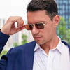 A man wearing retro vintage metal frame sunglasses with brown lenses and a white shirt.
