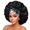 A woman wearing an extra large satin sleep bonnet with an elastic band in black and white patterns.