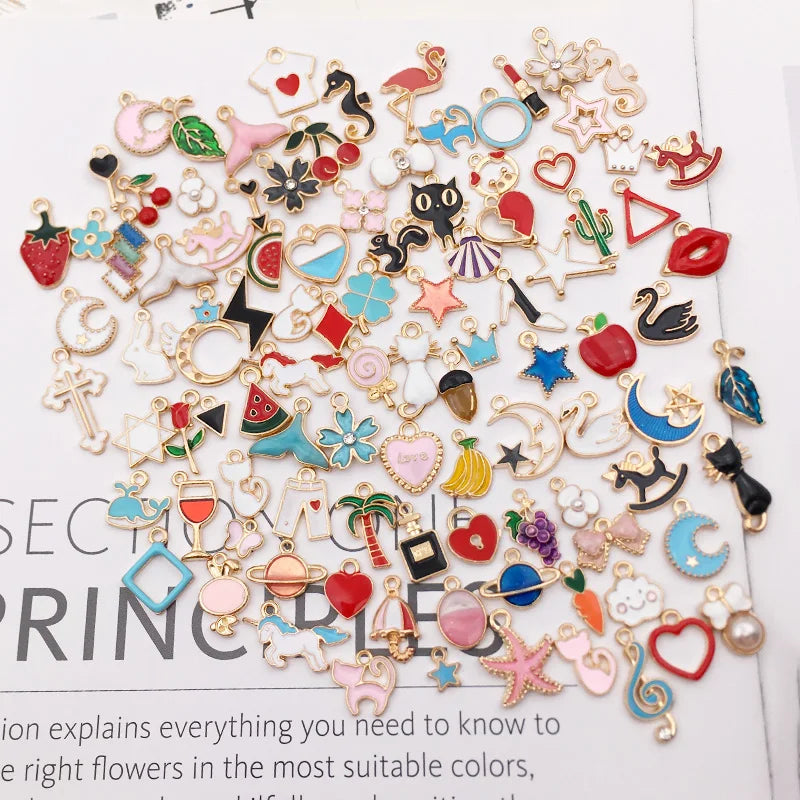 Collection de perles et charms en émail mélangés pour la fabrication de bijoux, présentés sur une surface blanche.