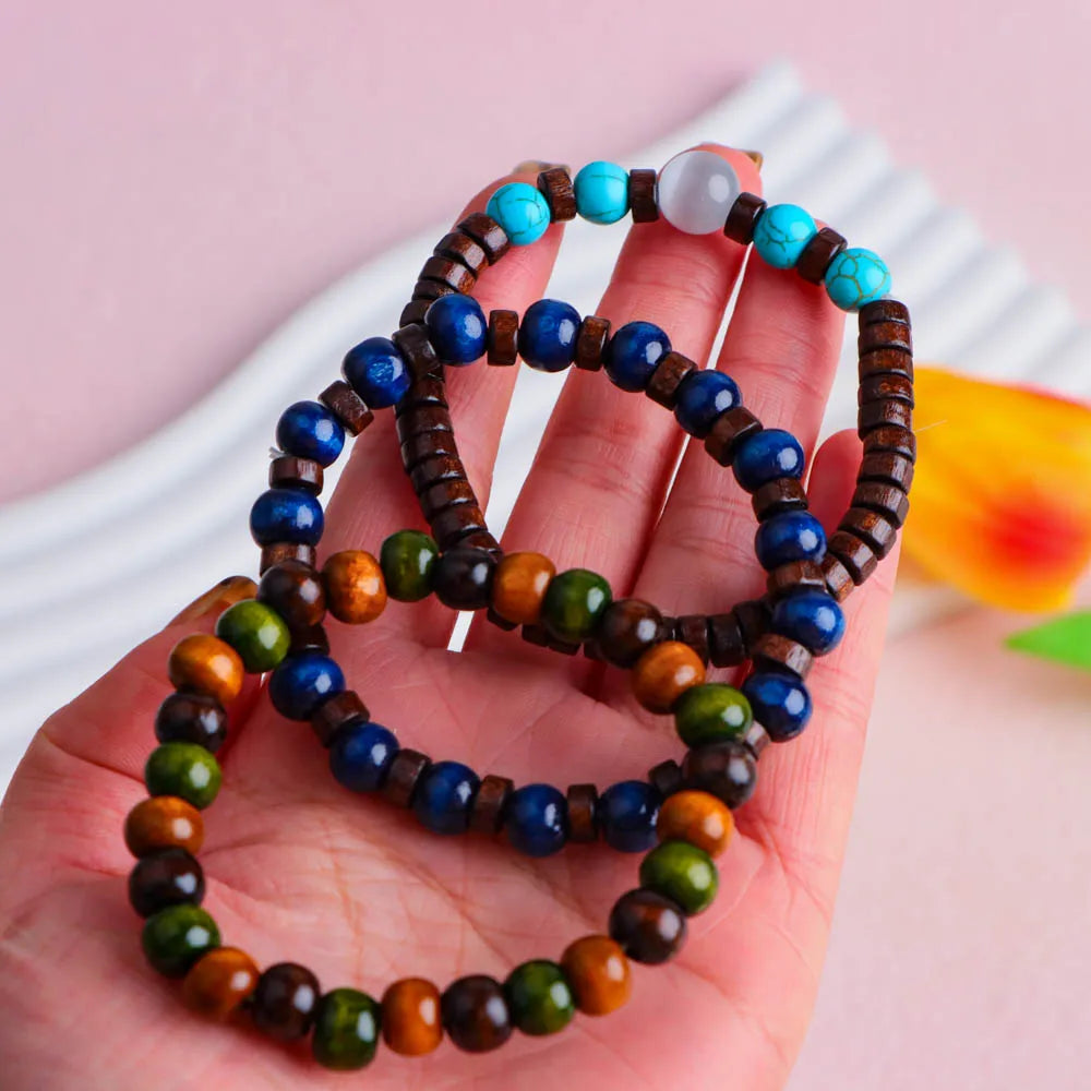A hand holds several fashion elastic wood bead bracelets featuring various shades of blue, green, and brown.