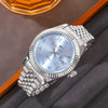 A silver Riccetto quartz wristwatch with a metal bracelet displayed on a gray fabric next to an orange object.